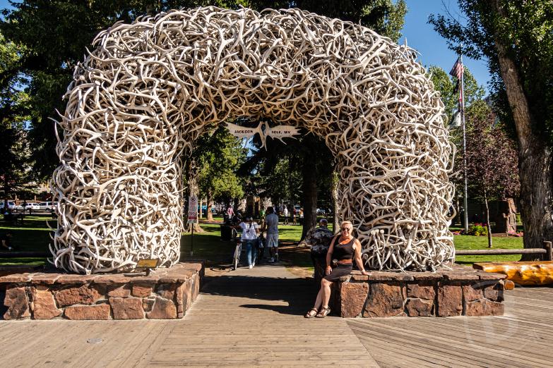 Jackson | Jeannette vor einem Elch-Geweih-Bogen